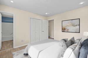Bedroom featuring light wood-style flooring, recessed lighting, ensuite bathroom, and a closet