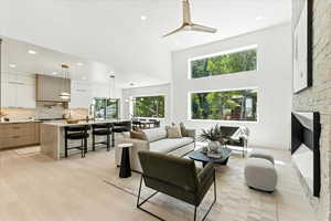 Living area featuring recessed lighting, light wood finished floors, a large fireplace, ceiling fan, and a towering ceiling