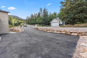 View of asphalt driveway featuring a forest view