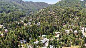 Aerial view of property and surrounding area featuring mountains and a forest