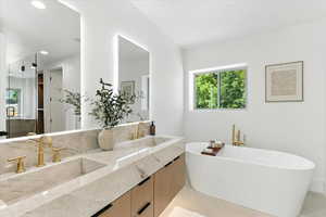Full bath featuring double vanity, a freestanding bath, recessed lighting, and a stall shower