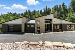 View of front of property featuring board and batten siding, a garage, log exterior, and asphalt driveway