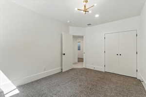 Unfurnished bedroom with carpet floors, a chandelier, a closet, and recessed lighting