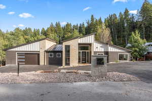 View of front of home featuring board and batten siding, stone siding, an attached garage, driveway, and a standing seam roof