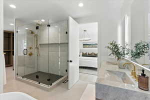 Ensuite bathroom with double vanity, a stall shower, light tile patterned flooring, recessed lighting, and a freestanding bath