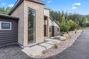 Entrance to property with stone siding, faux log siding, and board and batten siding