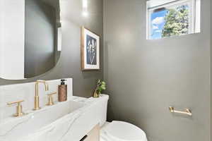 Half bathroom featuring vanity and toilet