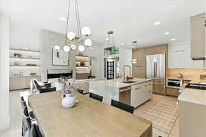 Kitchen with light stone counters, decorative light fixtures, open floor plan, appliances with stainless steel finishes, and a fireplace