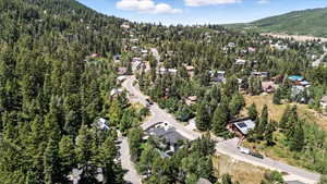 Aerial view of property's location with a mountain backdrop and a heavily wooded area