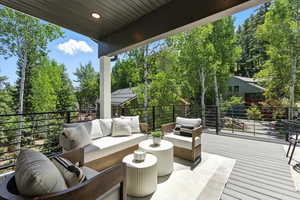 Wooden terrace featuring an outdoor hangout area, view of scattered trees, and a patio