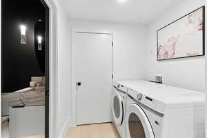 Laundry area with light wood-style flooring, washer and dryer, and arched walkways