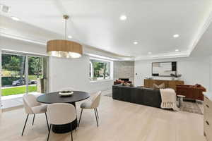 Dining room featuring recessed lighting, light wood finished floors, a large fireplace, and a tray ceiling