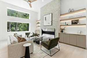 Living room with a ceiling fan, a towering ceiling, light wood finished floors, and recessed lighting