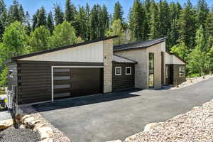 Garage featuring a view of trees and driveway