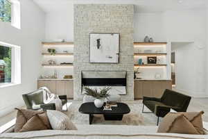 Living room featuring a fireplace, light wood-style flooring, and a towering ceiling