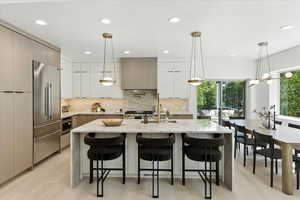 Kitchen with light stone counters, decorative light fixtures, white cabinets, tasteful backsplash, and recessed lighting