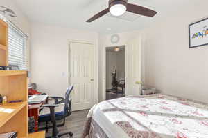 Bedroom featuring dark wood-style flooring, a ceiling fan, and a desk