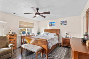 Bedroom with dark wood-type flooring, a textured ceiling, and a ceiling fan