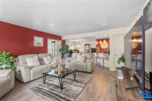 Living room featuring a textured ceiling, light wood-style flooring, and a chandelier