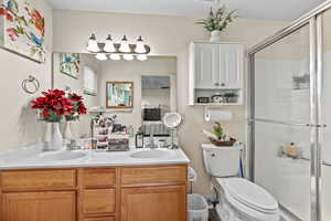 Full bath featuring double vanity, a stall shower, and connected bathroom