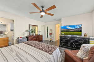 Bedroom featuring a textured ceiling, dark wood-type flooring, ceiling fan, and ensuite bathroom