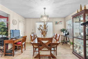 Dining area with a textured ceiling, light wood finished floors, and a chandelier