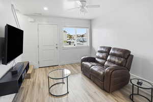 Living area with light wood-type flooring and a ceiling fan