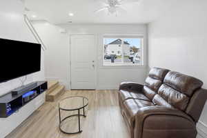 Living area with light wood finished floors, stairway, a ceiling fan, and recessed lighting
