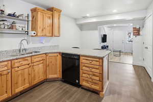 Kitchen featuring light stone countertops, dark wood-style floors, dishwasher, a peninsula, and recessed lighting