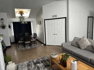 Tiled living room featuring lofted ceiling and baseboards