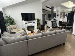 Living room with a premium fireplace, vaulted ceiling, and tile patterned floors