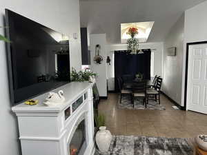 Tiled dining area with a textured wall, lofted ceiling, and a textured ceiling