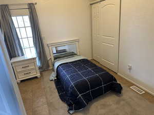Bedroom featuring a textured wall and dark tile patterned flooring