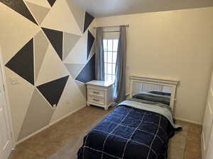 Tiled bedroom featuring a textured wall and baseboards