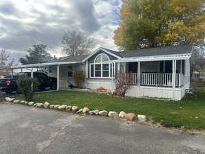 View of front facade featuring a front yard, a carport, and covered porch