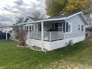 View of home's exterior featuring covered porch, a yard, and roof with shingles