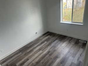 Unfurnished room featuring wood finished floors and a textured wall