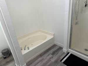 Bathroom featuring a garden tub, a stall shower, and dark wood finished floors