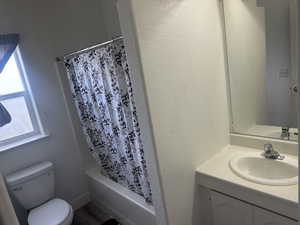 Bathroom featuring shower / bath combo with shower curtain, vanity, and a textured wall