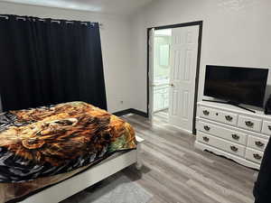 Bedroom featuring light wood finished floors and ensuite bath