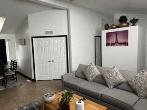 Living area with lofted ceiling, tile patterned flooring, and a textured ceiling