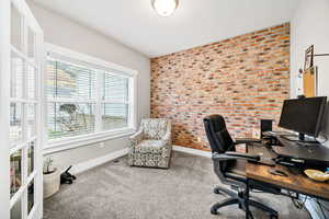 Home office featuring brick wall and carpet flooring