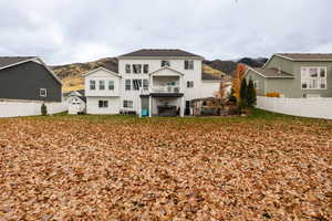 Rear view of property featuring a fenced backyard, a mountain view, and a balcony