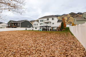 Back of house featuring a fenced backyard, a balcony, a mountain view, and a patio