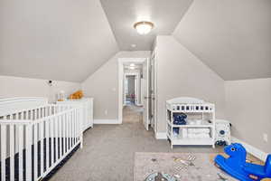 Bedroom with light colored carpet, and vaulted ceiling