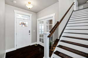 Foyer with stairway, dark wood-type flooring, and french doors