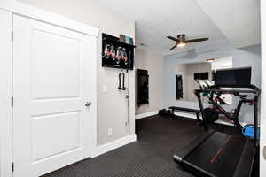 Workout room featuring ceiling fan and a textured ceiling