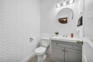 Half Bathroom featuring vanity and wallpapered walls