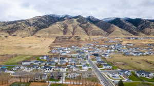 Aerial view of property and surrounding area featuring nearby suburban area and a mountain backdrop