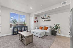 Living room featuring a textured ceiling, recessed lighting, and light wood-style flooring